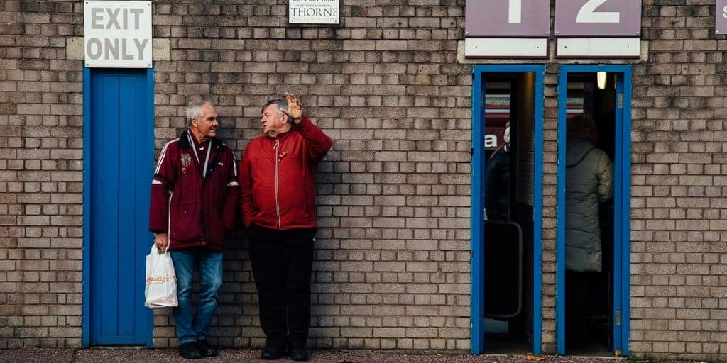 a couple of men standing next to a brick building
